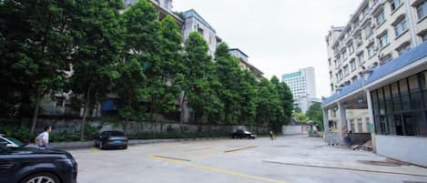 A parking lot with cars, a building with a blue roof, and trees.