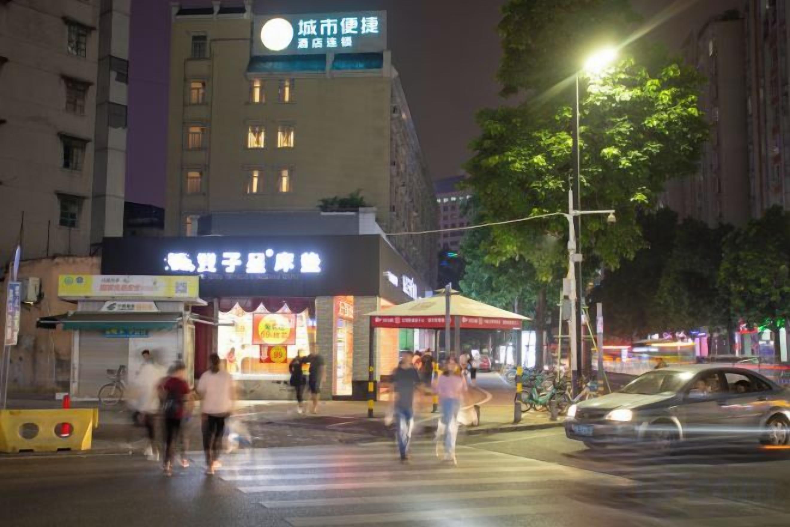 A street scene at night with a building that has a sign for a restaurant and a crosswalk.