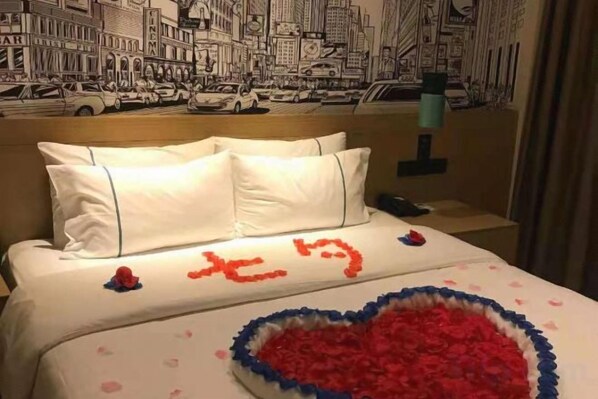 Habitación de hotel con una cama decorada con un adorno en forma de corazón y un mural de un paisaje urbano en la pared.