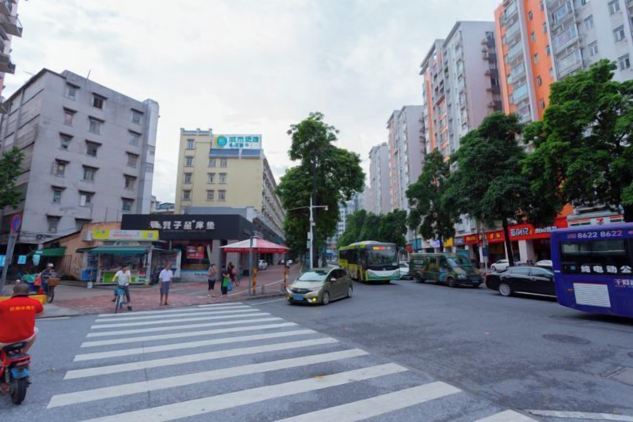 A street intersection with buildings, a crosswalk, and vehicles including buses and cars.