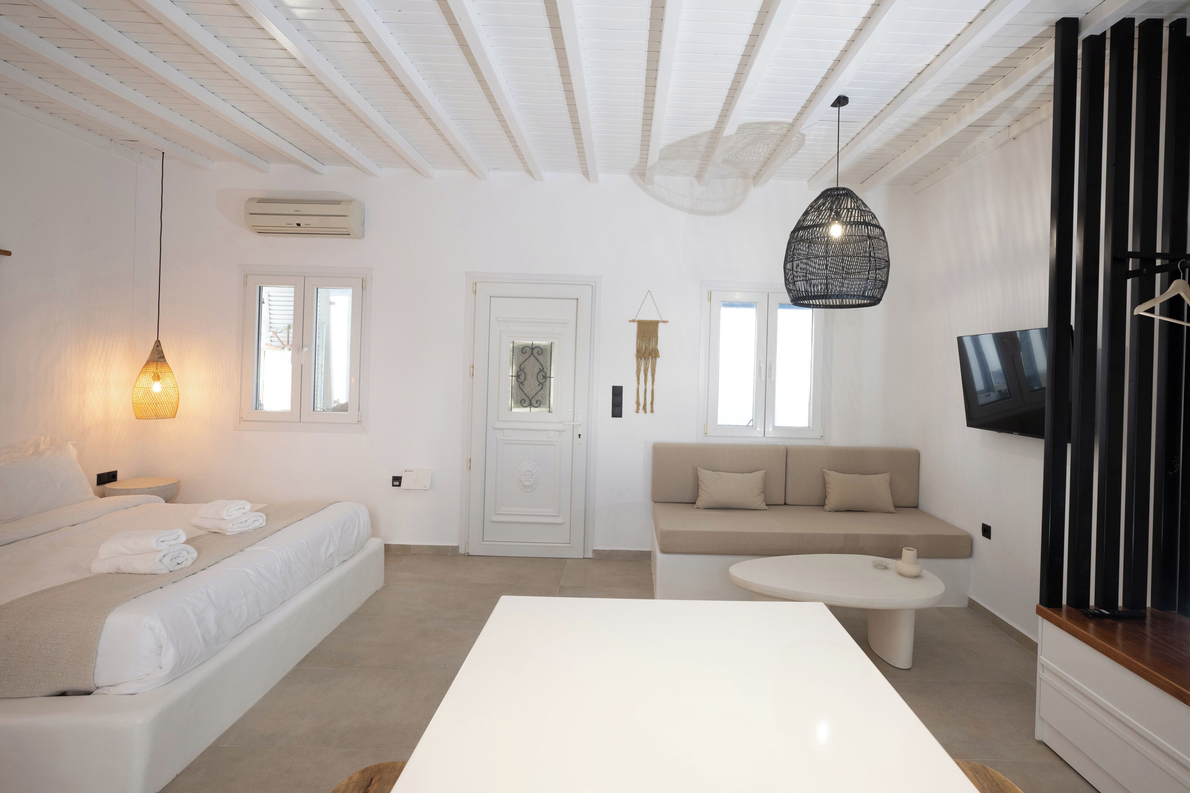 Un salon moderne et minimaliste, avec un canapé blanc, une table basse ronde et un téléviseur fixé au mur.