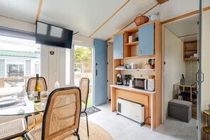 Ein kompakter Wohnbereich mit Essplatz, Küchenzeile und einem an der Wand befestigten Fernseher.