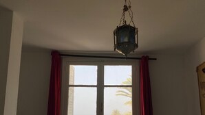 A room with a large window, a hanging lantern, a small table, and a bed with pillows. - Waterfront duplex with sea view EXTRAORDINARY (Monastir)