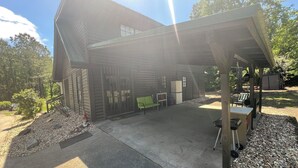 Una baita di legno con un portico coperto, sedute all'aperto e un piccolo deposito.