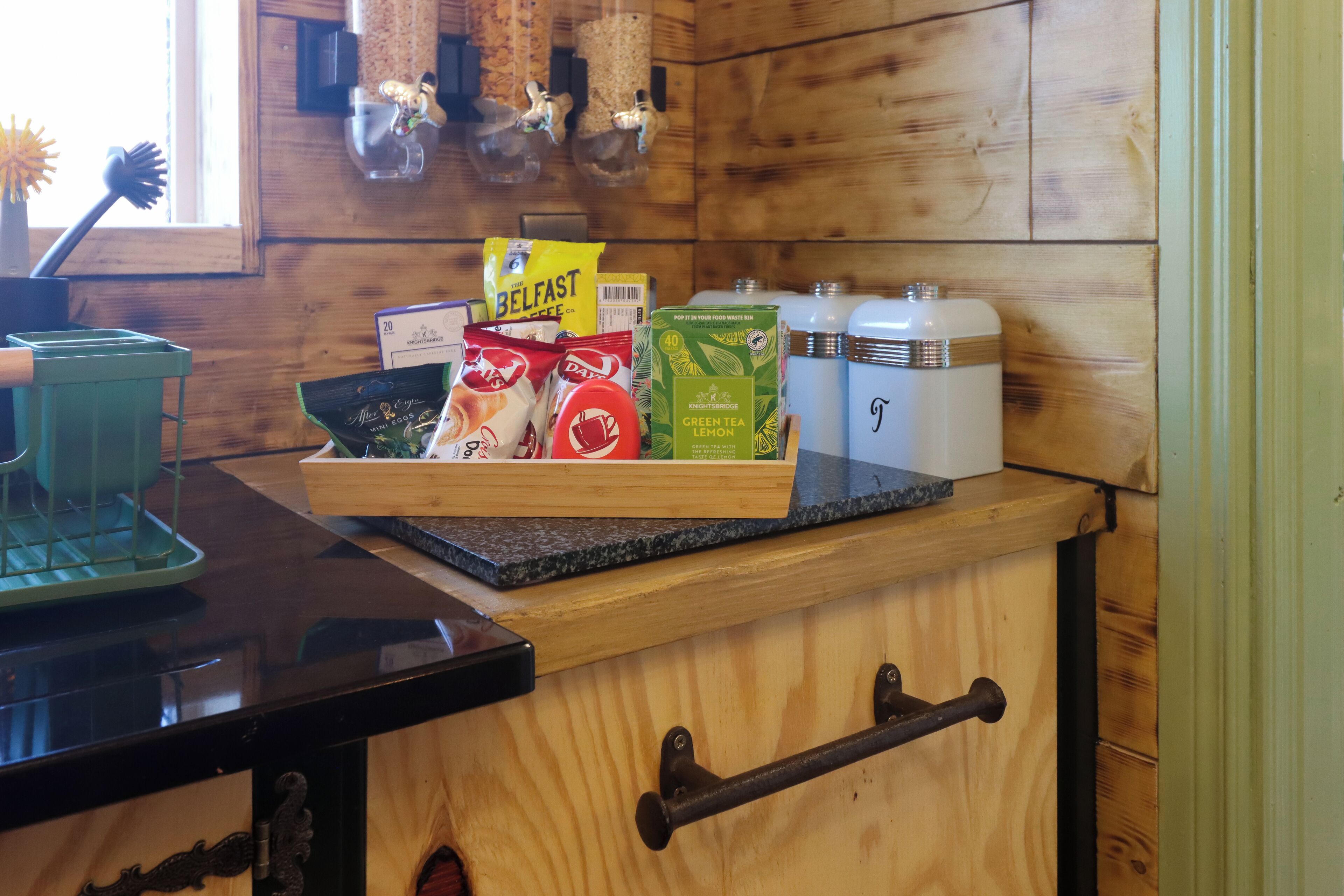 A kitchen counter with a tray of food items, including a bag of chips, a box of tea, and a container of green tea.