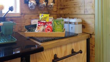 A kitchen counter with a tray of food items, including a bag of chips, a box of tea, and a container of green tea.