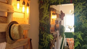 Un intérieur rustique avec des poutres en bois, des luminaires suspendus et un miroir qui reflète une pièce avec une fenêtre et une plante.
