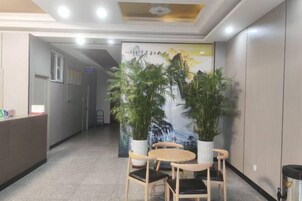 A reception area with a reception desk, two potted plants, and a mural on the wall.
