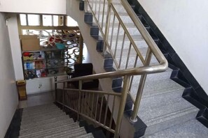 A staircase with a metal handrail and a shop at the bottom. - Wangting Express Hotel (Zhengding)