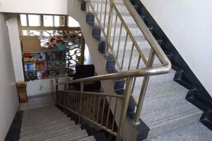 Una escalera con barandilla metálica y una tienda al final.