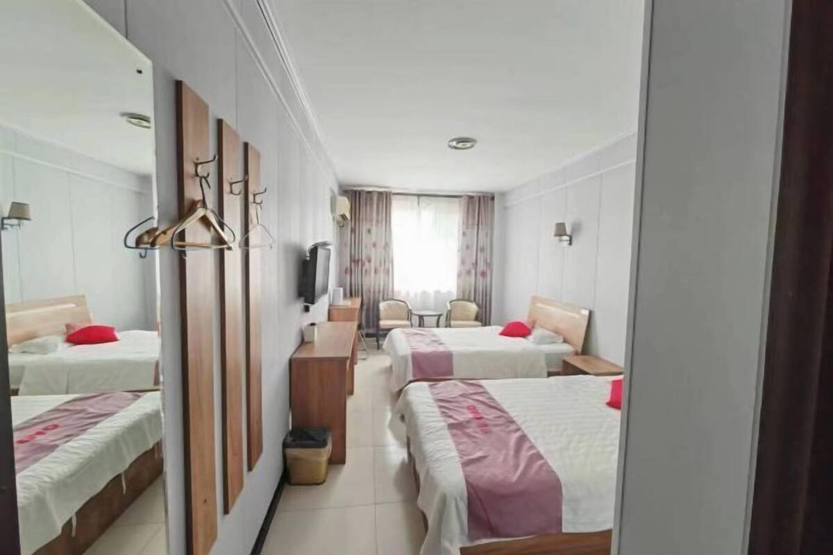 Ett hotellrum med två sängar, ett skrivbord, en stol och en tv.