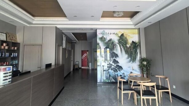 Un vestíbulo de hotel con una recepción, un mural de una cascada y un área de descanso con sillas y una mesa.