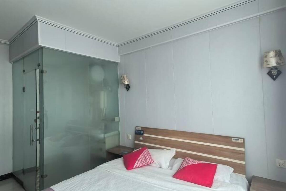 Ett hotellrum med en säng, en duschkabin med glasväggar och ett nattduksbord.