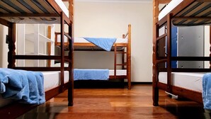 Une chambre de dortoir avec des lits superposés, un plancher en bois et des casiers.