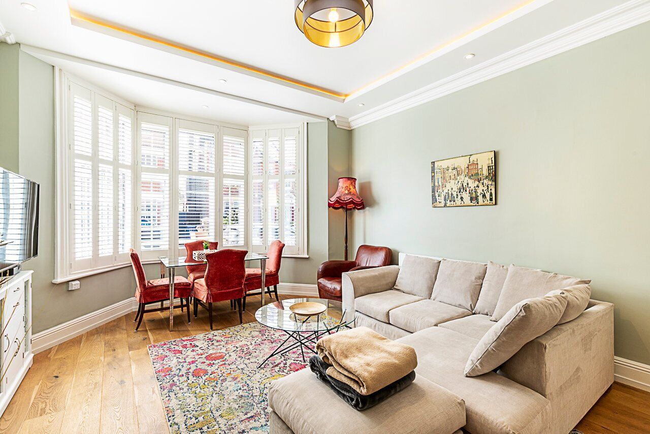 A living room with a sofa, chairs, a coffee table, and a window with blinds.