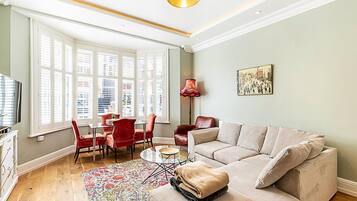 A living room with a sofa, chairs, a coffee table, and a window with blinds.