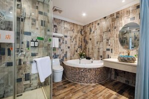 Ein modernes Badezimmer mit Duschkabine aus Glas, freistehender Toilette, rundem Whirlpool und Waschtisch mit Spiegel.