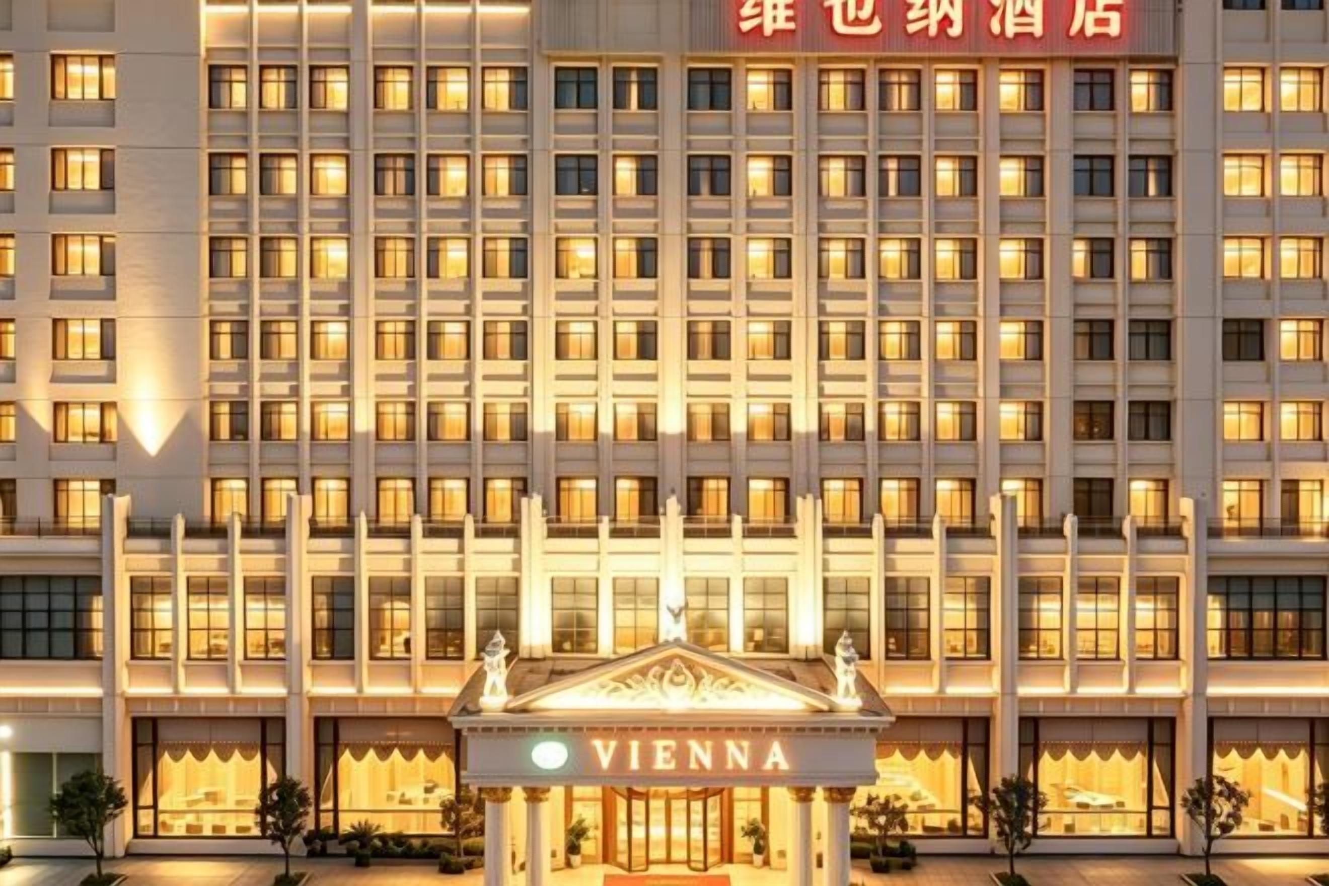 A multi-story hotel with a symmetrical facade, featuring a central entrance with a pediment and the name 'VIENNA' displayed.