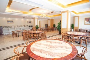 A hotel dining area with round tables and chairs, a chandelier, and a buffet counter. - Vienna Hotel (Wuxi Railway Station Huishan Scenic Spot) (Wuxi)