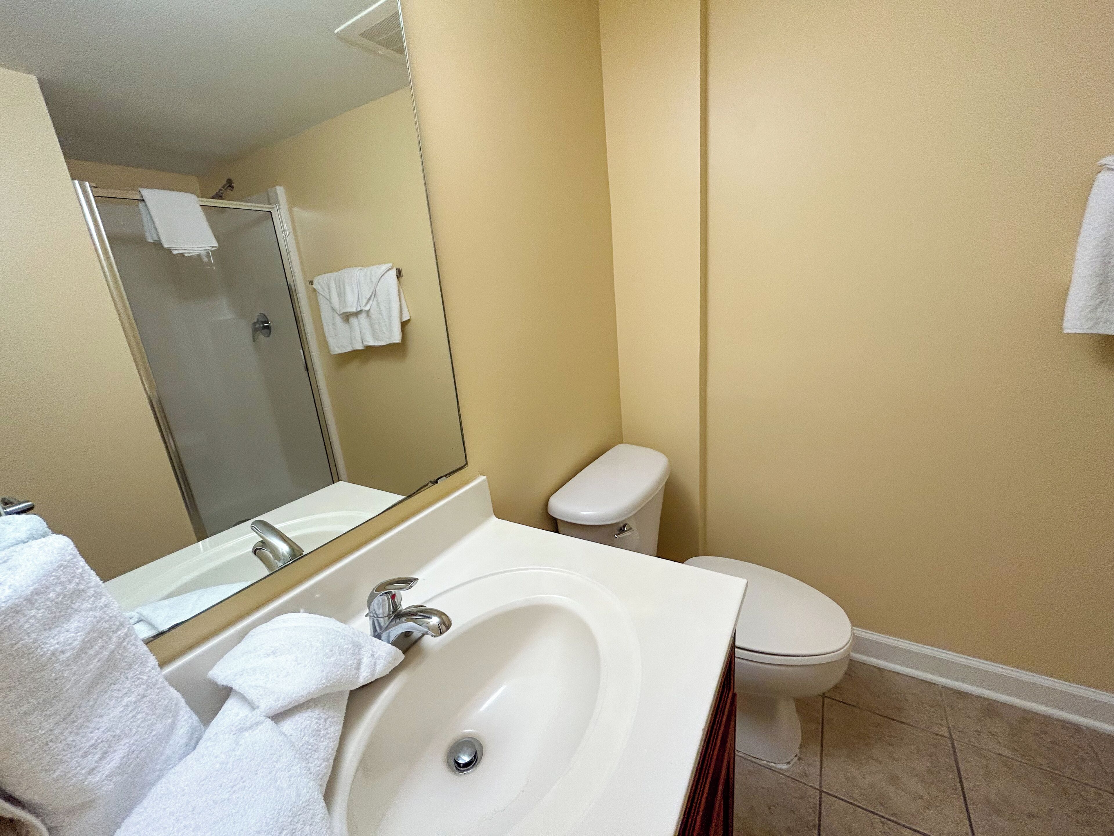 Un baño con lavamanos, espejo, inodoro y ducha.