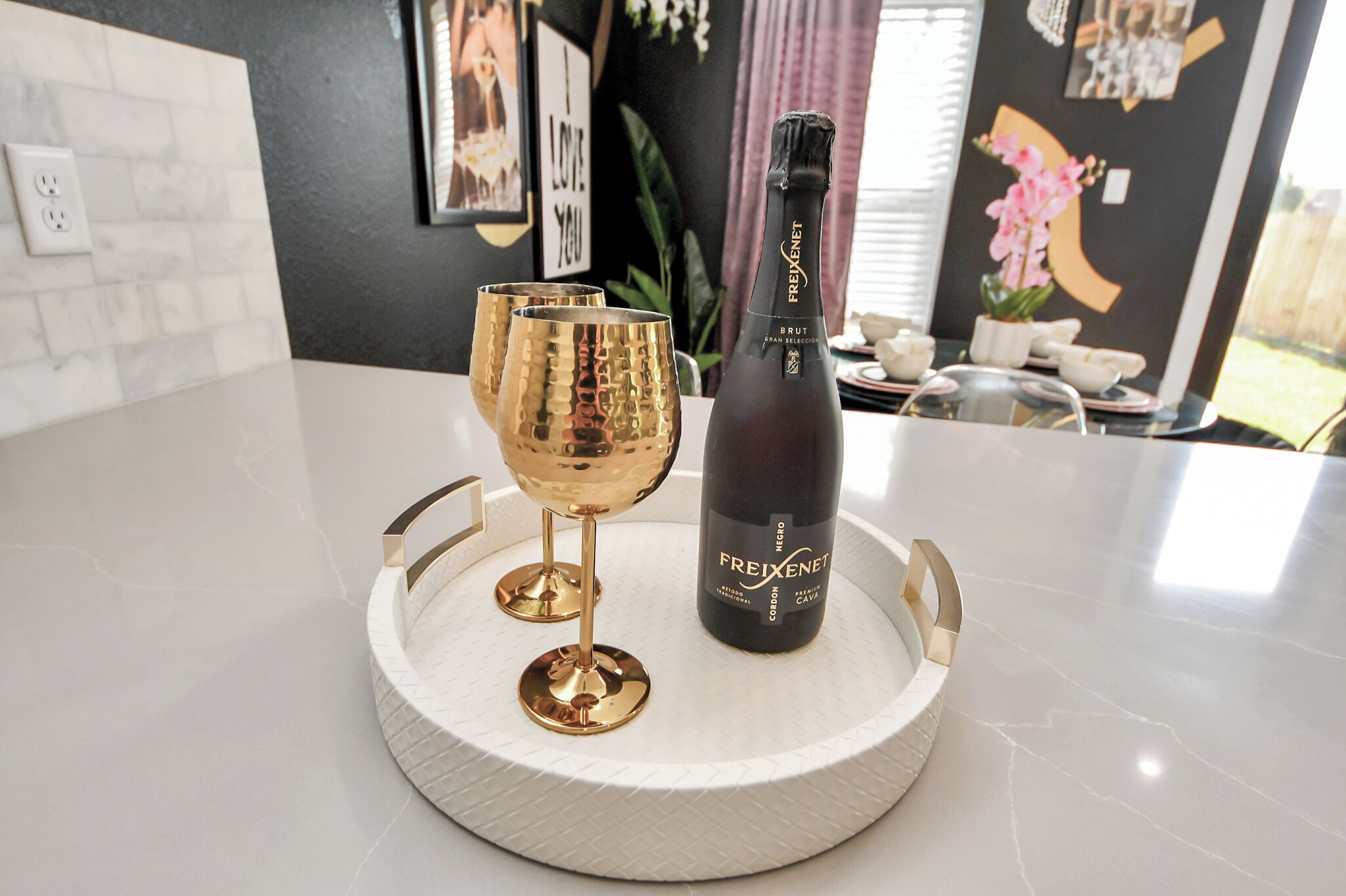 A bottle of Freixenet Brut champagne on a white tray with two gold glasses.