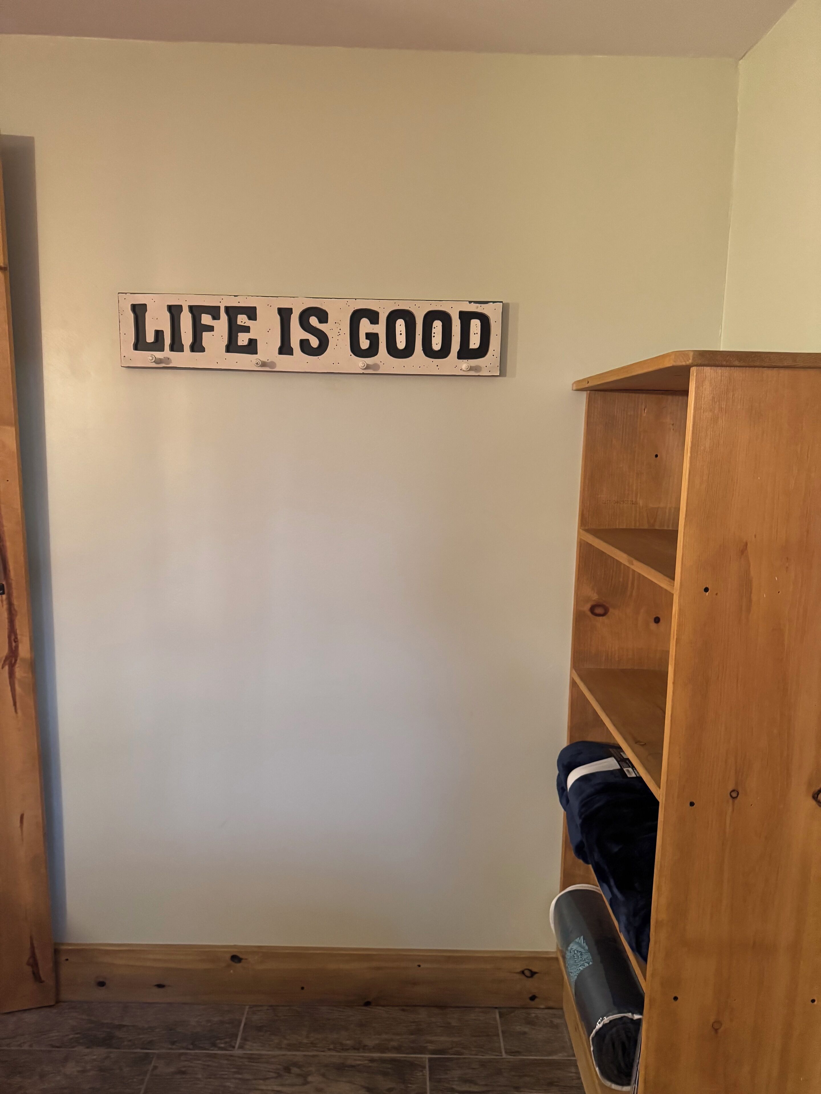A room with a wooden shelf unit and a motivational sign on the wall.