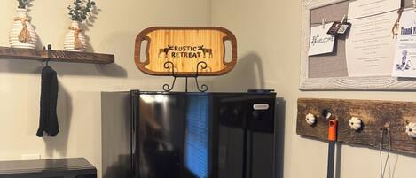Una cocina con un refrigerador negro, un microondas y un cartel de madera sobre el refrigerador que dice "Rustic Retreat".