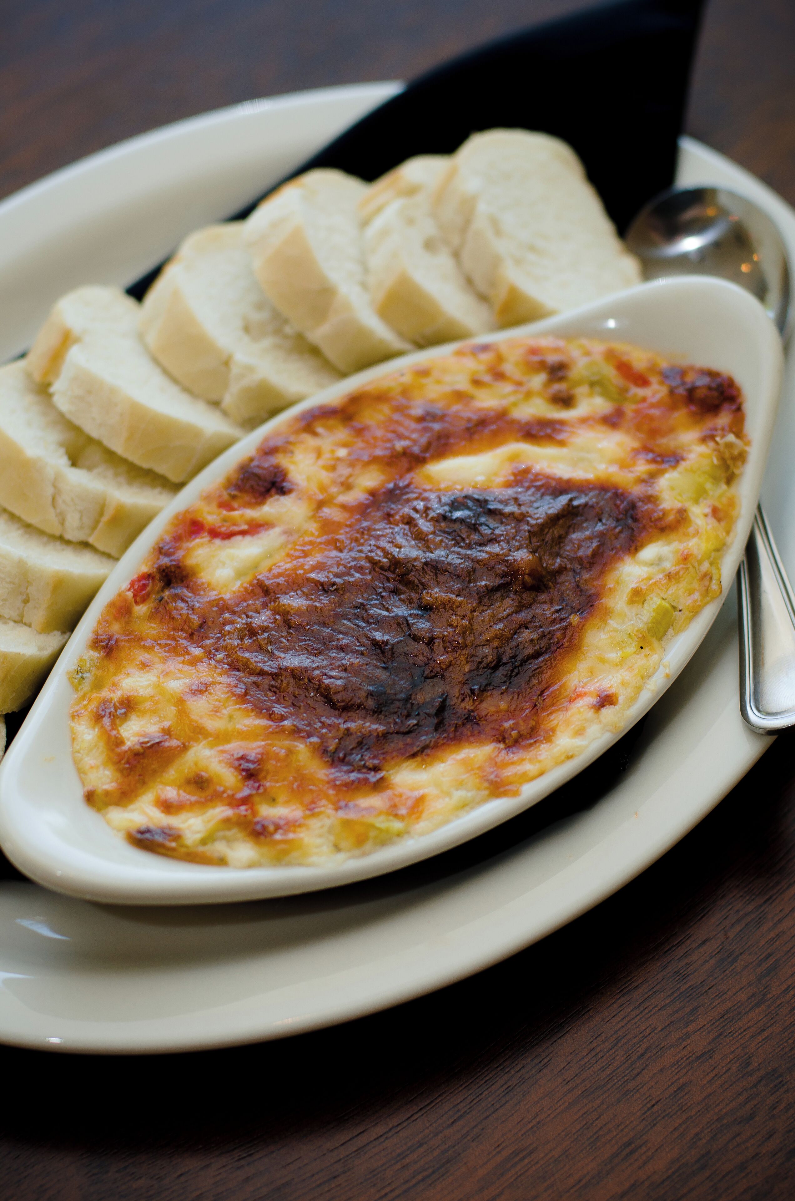 En portion bagt lasagne med gyldenbrun ost, serveret på en hvid, oval tallerken.
