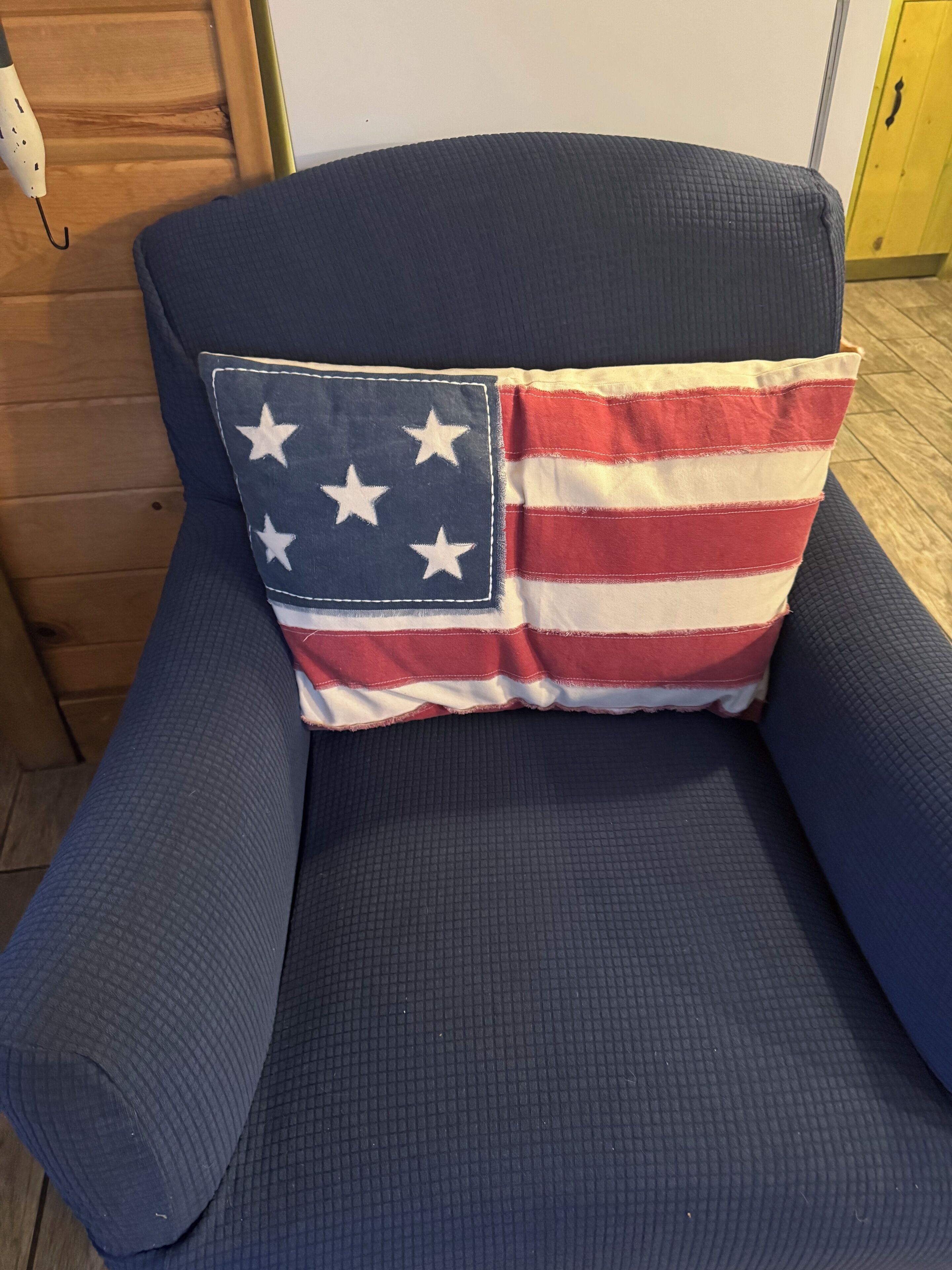 Un sofá azul con un cojín que presenta un diseño de la bandera estadounidense.