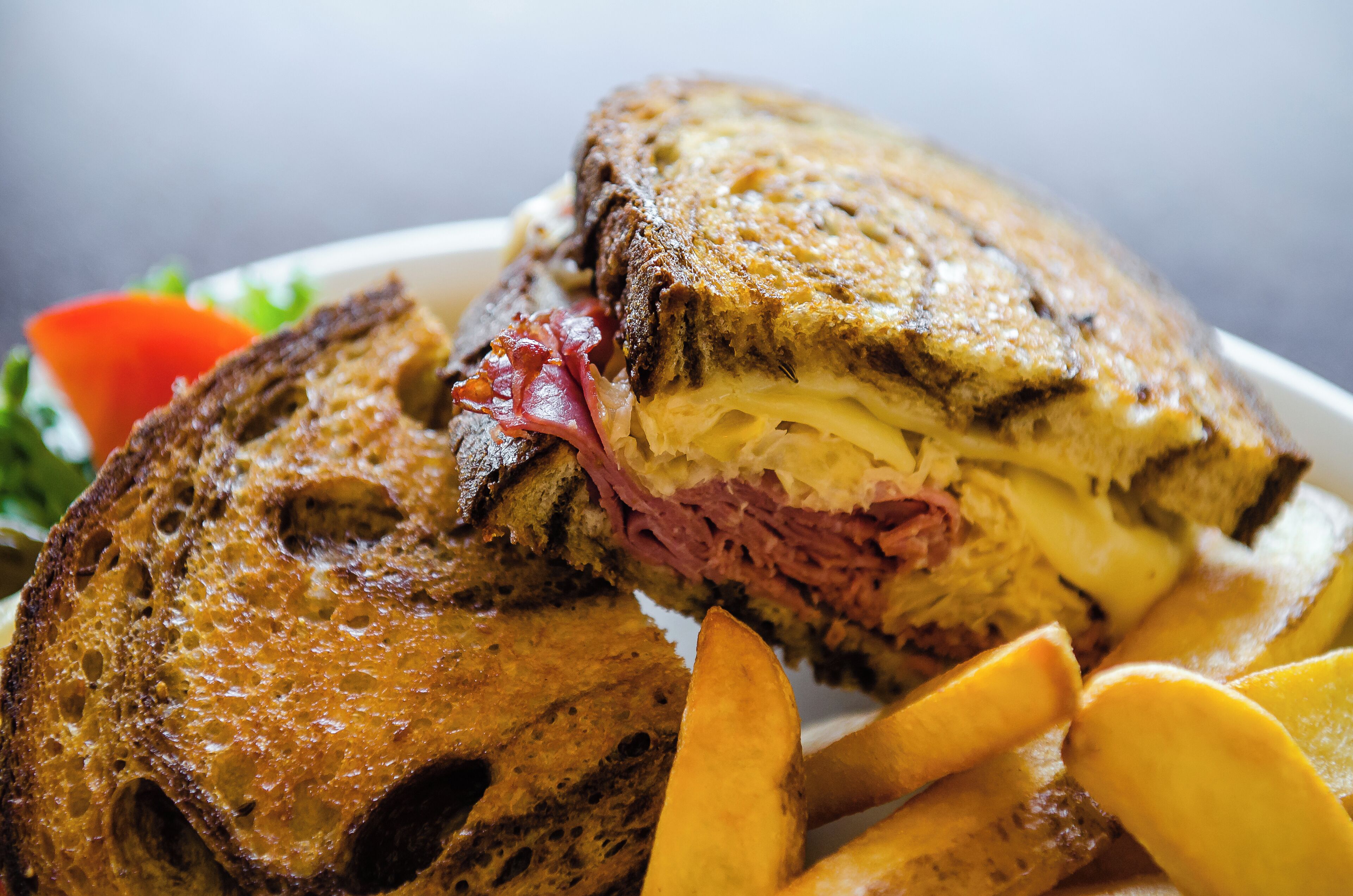 A sandwich with fries and a slice of tomato.