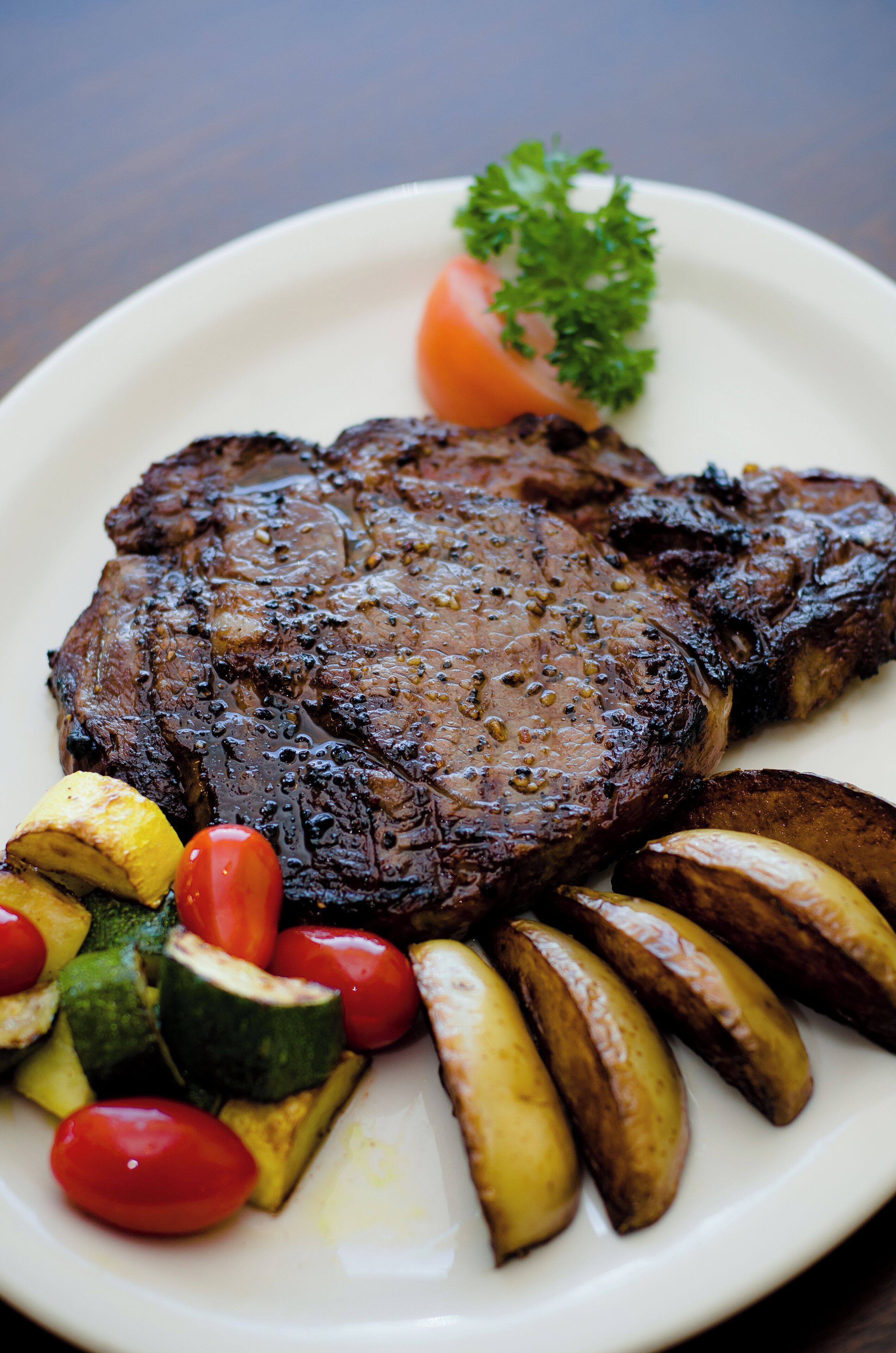 A plate with a grilled steak, roasted potatoes, and vegetables.