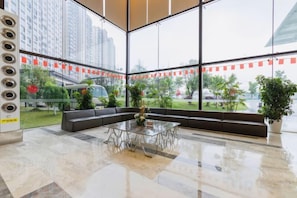 Un hall d’entrée spacieux avec un mur en verre, un coin salon et une table basse.
