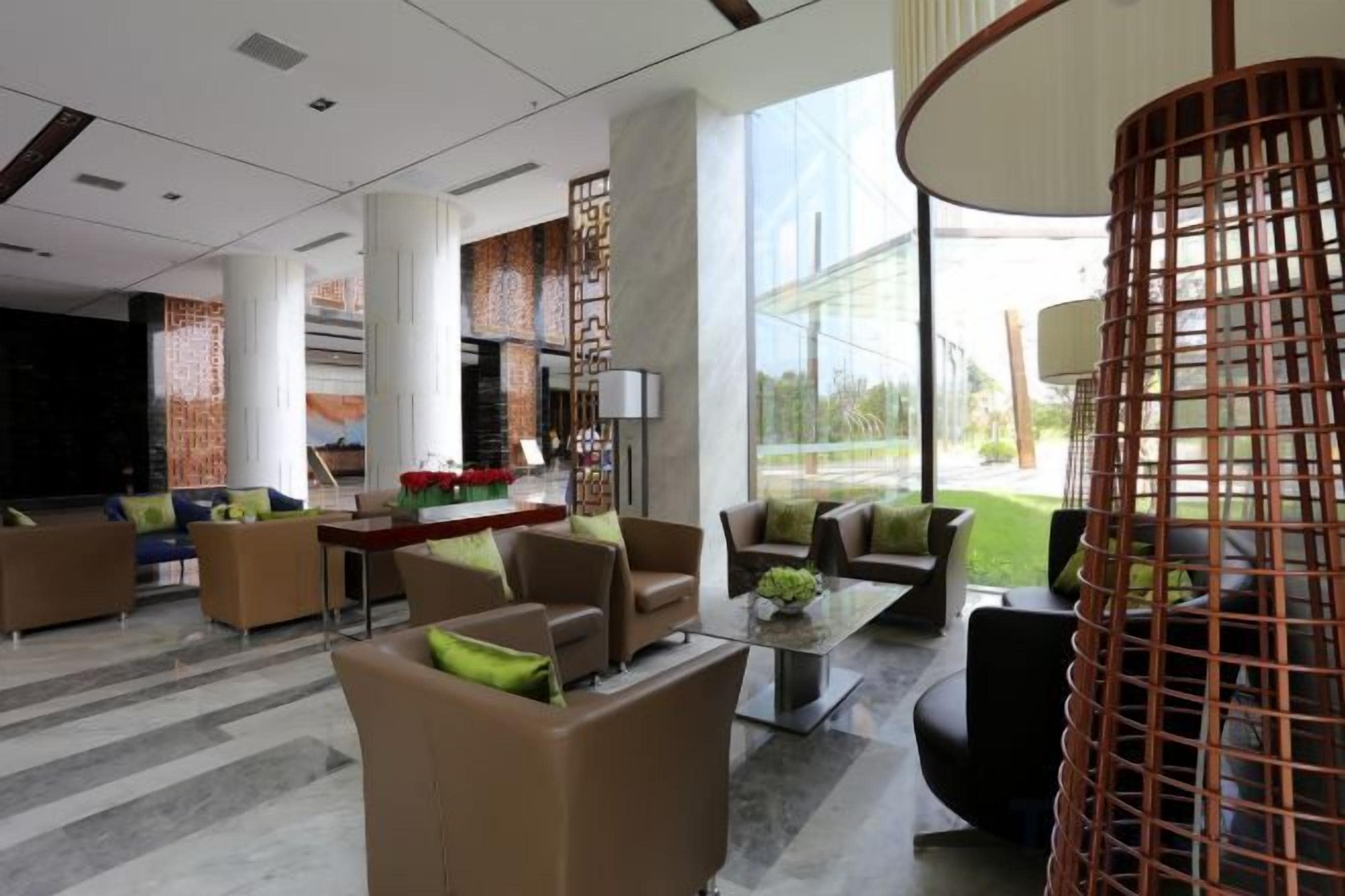 A modern lobby with seating areas, a coffee table, and a large window providing a view of the outdoors.