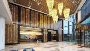 A spacious lobby with a reception desk, modern chandeliers, and seating areas. - Blue Bay Hotel (Zhangjiajie)