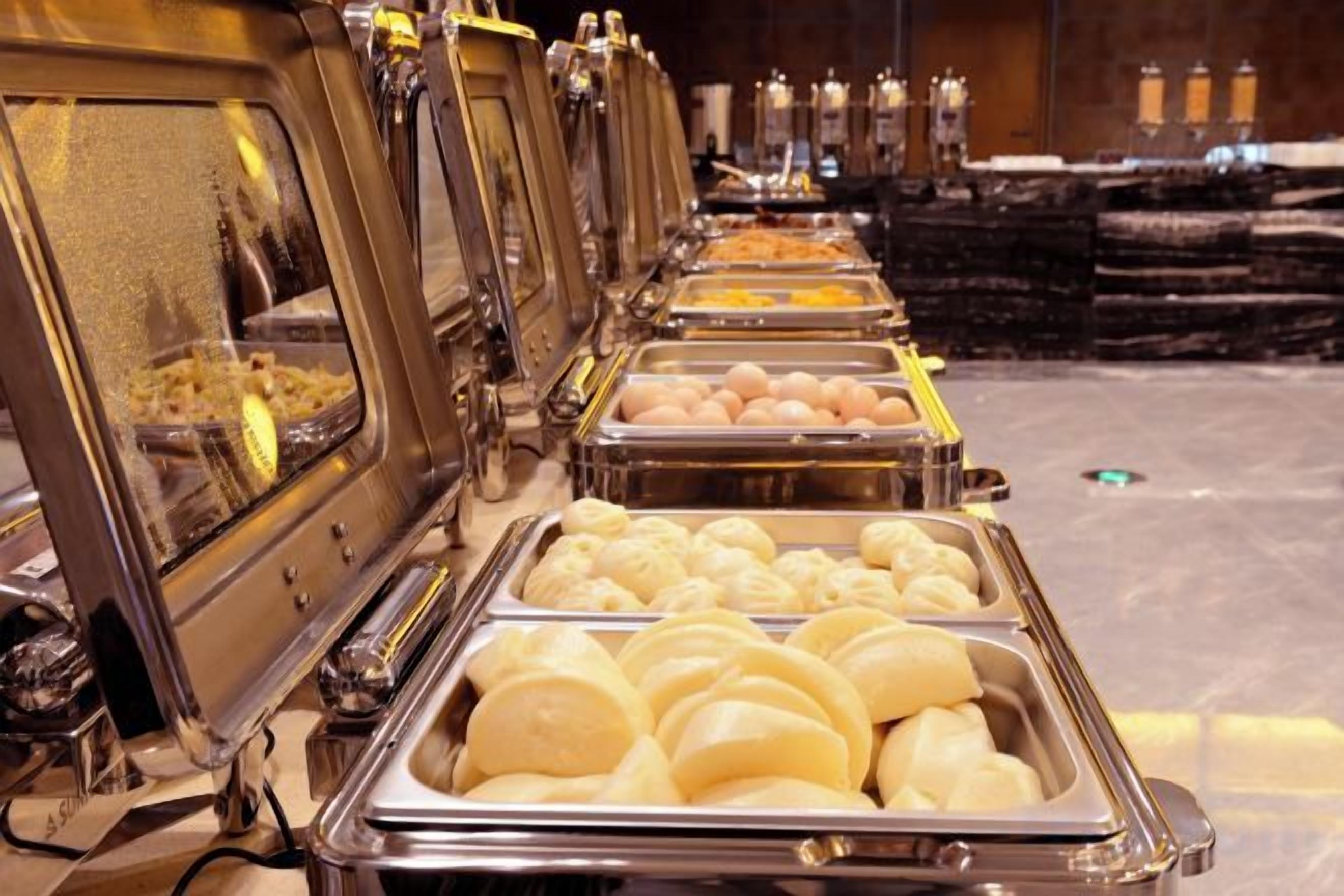 Una linea di buffet con diversi cibi, tra cui pane e uova.