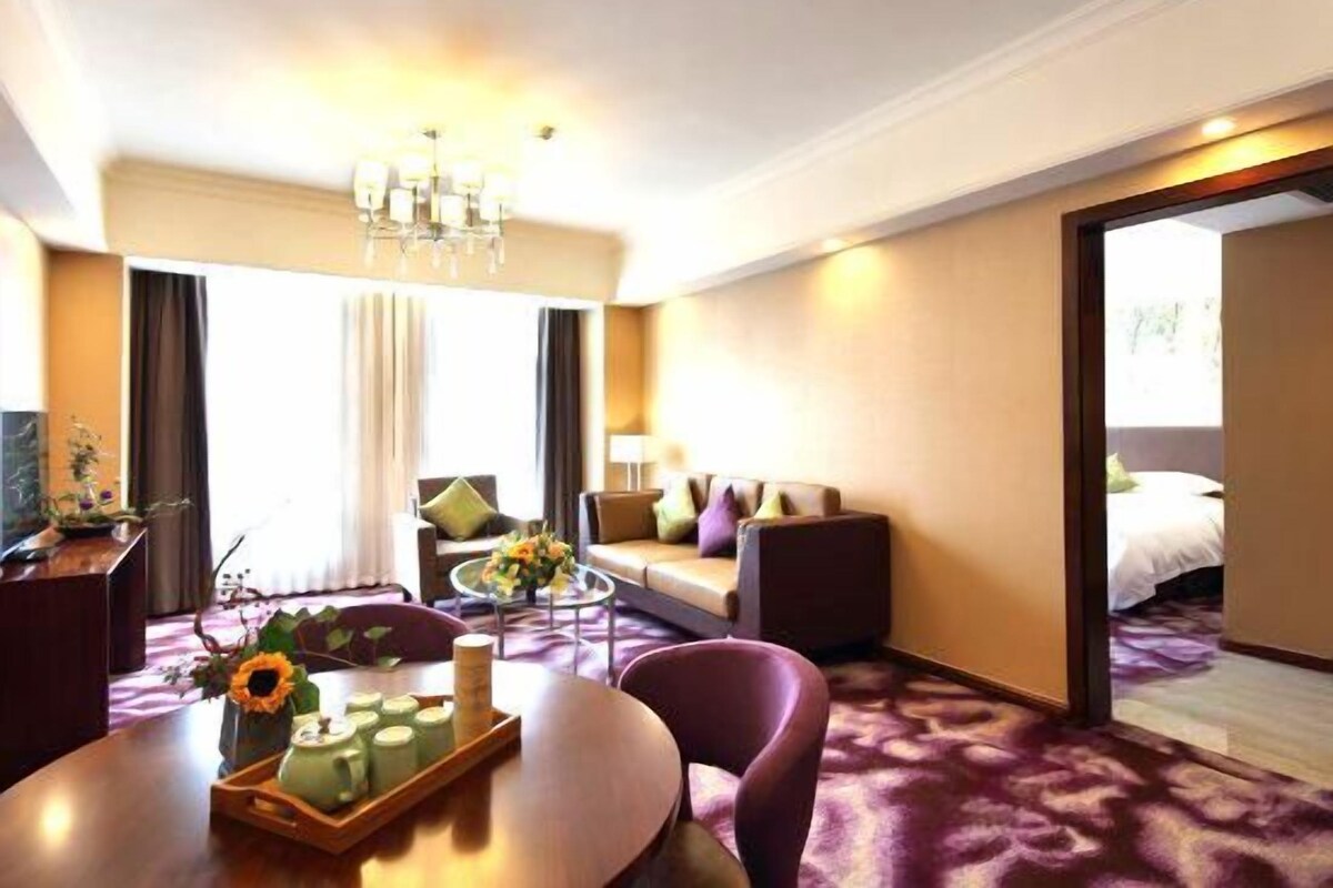 Hotelkamer met een zithoek, een bank, een kroonluchter en uitzicht op de omgeving.