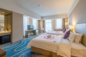 Een hotelkamer met twee bedden, een bureau, een televisie en een badkamer.