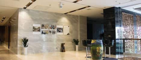Un vestíbulo moderno con pared de mármol, zona de estar y una partición de vidrio.