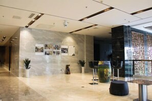 Un hall d’entrée moderne avec un mur en marbre, un espace salon et une cloison en verre.