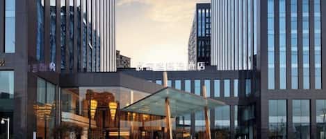 A modern hotel with a glass facade, large windows, and a covered entrance area.