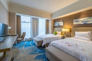 A hotel room with two beds, a desk, a chair, and a TV. - Blue Bay Hotel (Zhangjiajie)