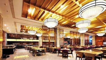 Un restaurante espacioso con techos altos, candelabros y diferentes opciones de asientos.