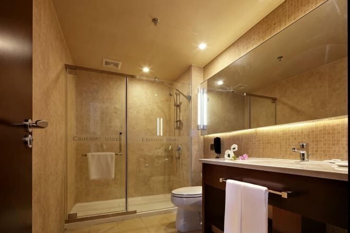 A modern bathroom with a glass shower enclosure, a toilet, a sink with a mirror, and a towel rack.