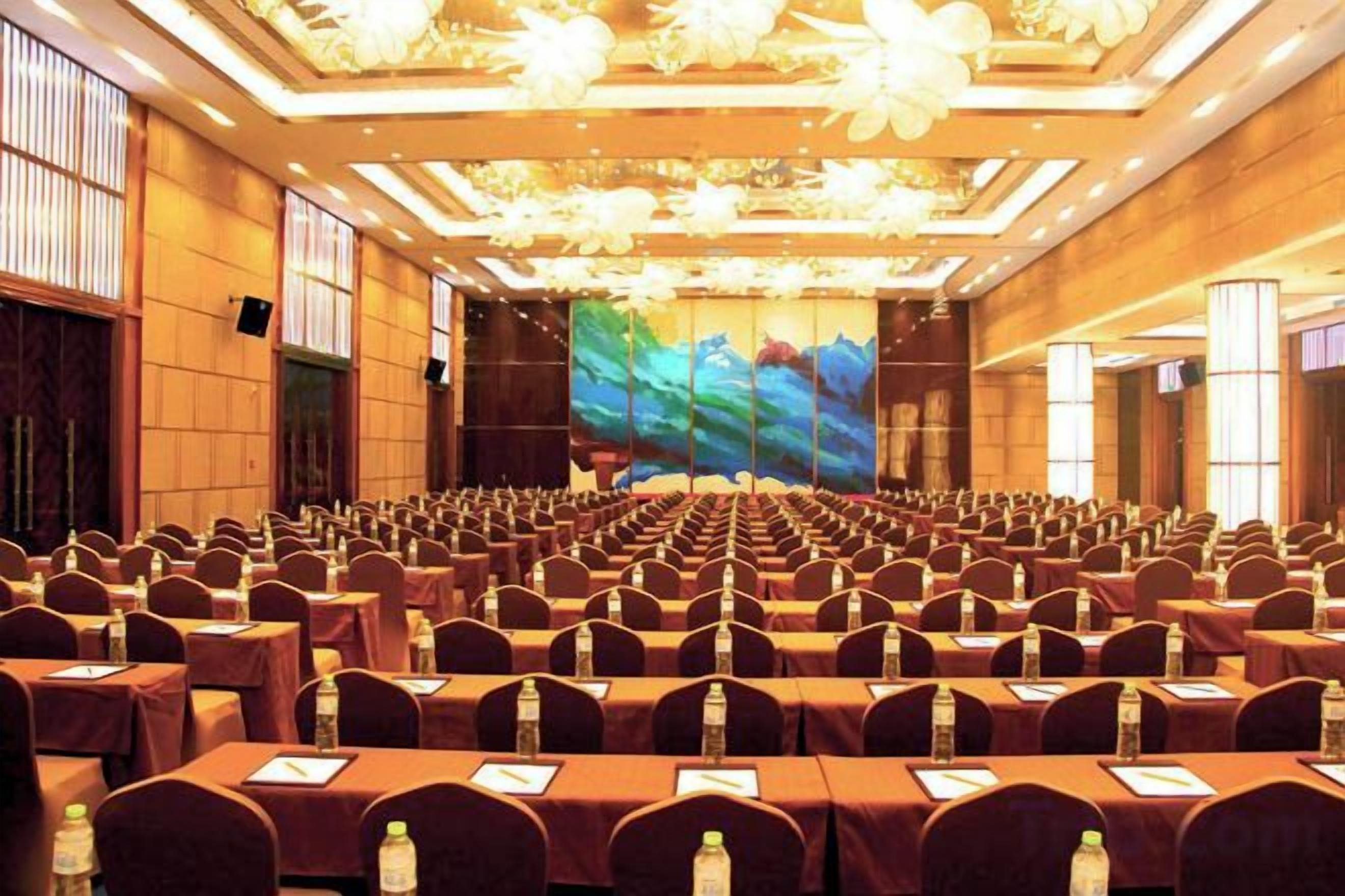 A conference room with rows of tables and chairs, a large screen, and a wooden interior.