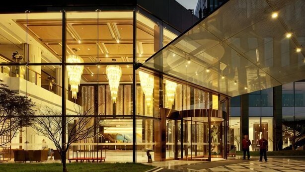 A modern building with large glass windows, a visible lobby area, and a staircase leading to upper floors. - Blue Bay Hotel (Zhangjiajie)