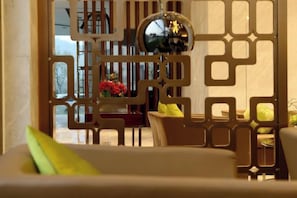 Une pièce comprenant un lit, une chaise, une table ornée de fleurs et un élément de séparation décoratif.