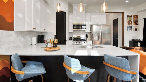 A modern kitchen with white cabinets, a central island, and pendant lighting.