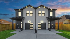 A two-story house with a garage, a satellite dish, and a well-maintained lawn.