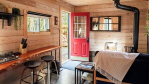 Een gezellig chaletinterieur met houten details, een rode deur, een keuken met krukken en een open haard.