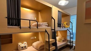 Camera con letto a castello, una scala, un piccolo finestrino e un punto luce a parete.